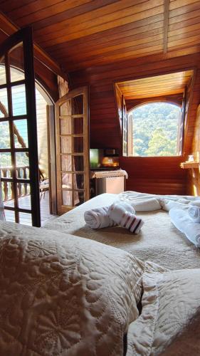 a bedroom with a large bed with a large window at Hortênsias da Serra Pousada in Nova Friburgo