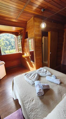 a bedroom with a bed with towels on it at Hortênsias da Serra Pousada in Nova Friburgo