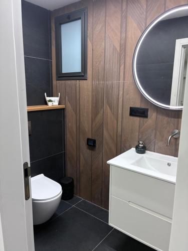 a bathroom with a toilet and a sink and a mirror at Quiet spot in Qiryat Ata