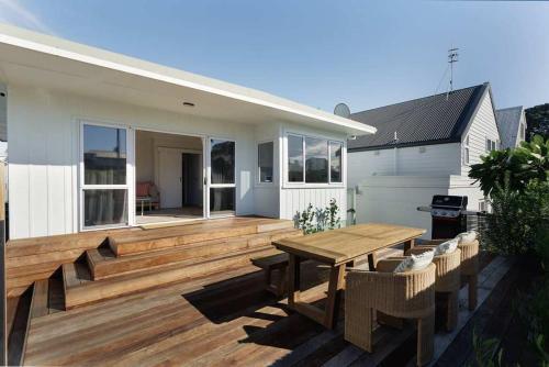 a wooden deck with a wooden table and chairs at The Sun Deck Five Star Focused Downtown Location in Mount Maunganui