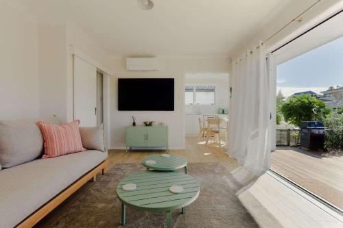 a living room with a couch and a table at The Sun Deck Five Star Focused Downtown Location in Mount Maunganui