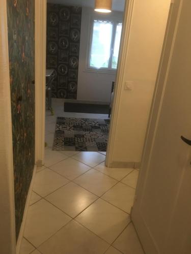 ein Flur mit Fliesenboden und einem Fenster in der Unterkunft APPARTEMENT 3 LITS Parking Proche Rouen Dock in Canteleu