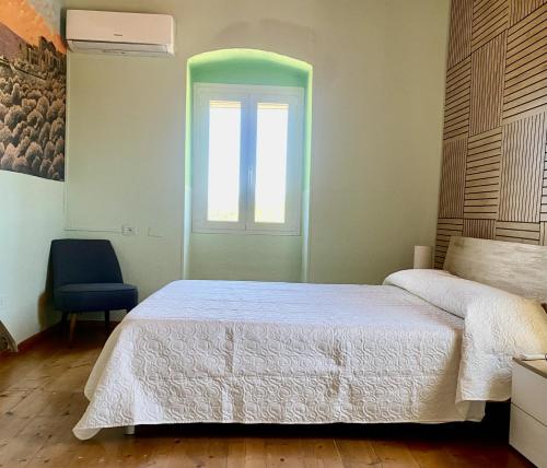 a bedroom with a bed and a window and a chair at Sweet Home Spalmatore in Carloforte