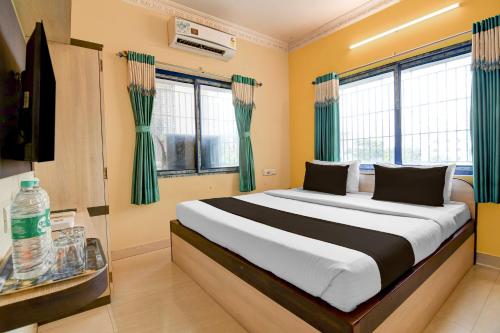 a bedroom with a large bed with green curtains at Hotel O Shyam sundar Hotel in kolkata
