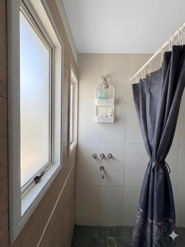 a bathroom with a shower curtain and a window at Link Cordoba Hostel in Córdoba