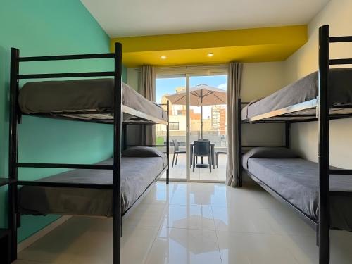 a room with two bunk beds and a table with an umbrella at Link Cordoba Hostel in Córdoba