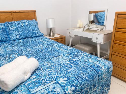 a bedroom with a blue and white bed and a desk at SUITE 1, BLUE PAVILION - Steps to BEACH - NEW AC in West Bay