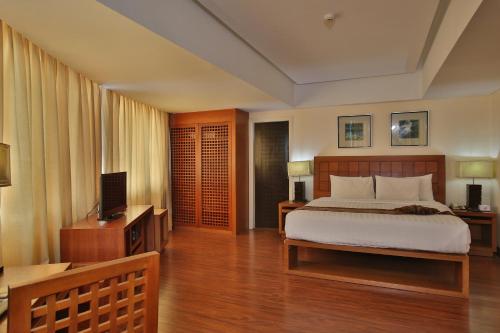 a bedroom with a bed and a desk and a television at Crown Regency Hotel & Towers in Cebu City