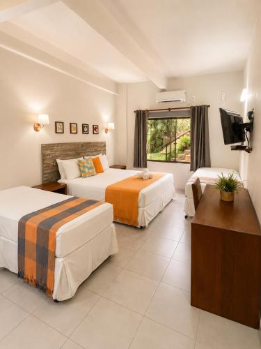 a hotel room with two beds and a flat screen tv at Pousada Santa Fe de Penedo in Penedo