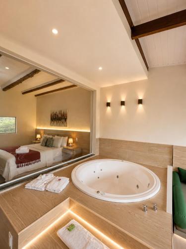 a large bathroom with a large tub and a bed at Pousada Santa Fe de Penedo in Penedo