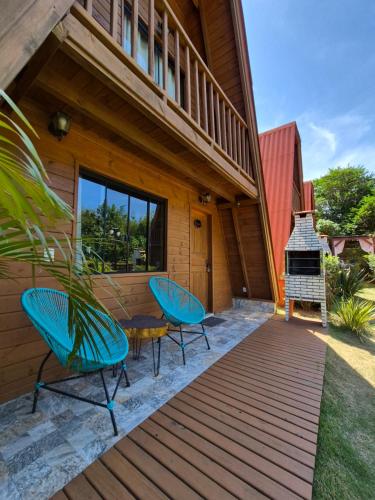 a deck with two chairs and a grill on a house at Chalés Ilha da Mata Pousada in Florianópolis