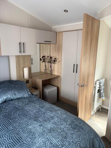 a bedroom with a bed and a desk and cabinets at Dune View Caravan in Lossiemouth