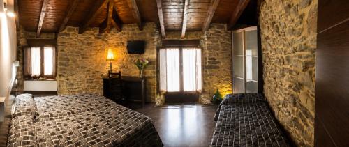 a bedroom with a bed and a stone wall at Hostal Ultreia in Villafranca del Bierzo