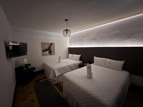 a hotel room with two beds and a tv at Hotel & Restaurante Teresàs Bistro in Antigua Guatemala