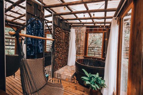 a screened in porch with a hammock and a tub at Chalé dos Alves in Morro Azul