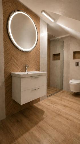 a bathroom with a sink and a toilet and a mirror at Nella - Pokoje gościnne in Ostrowo