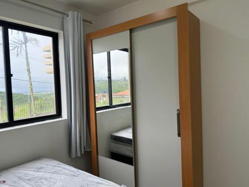 a bedroom with a mirror and a bed and a window at RESIDENCIAL MORADA DO VALE 03b in Garanhuns