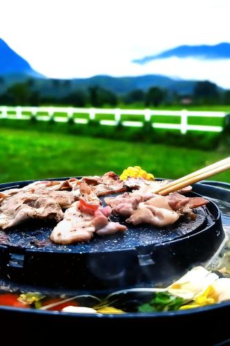 a bunch of meat on a grill with chop sticks at Western View Chiangdao Camping in Chiang Dao