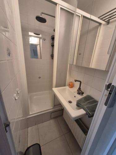 a white bathroom with a sink and a shower at Appartement Esmeralda in Knokke-Heist