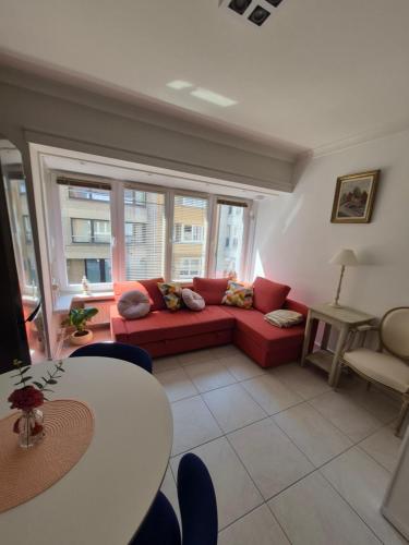 a living room with a red couch and a table at Appartement Esmeralda in Knokke-Heist