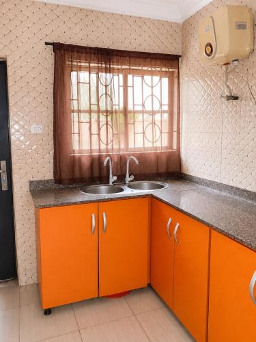 an orange kitchen with a sink and a window at Tee's Place in Coker