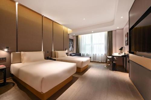 a hotel room with two beds and a desk at Atour Hotel Dalian Hi-tech Zone in Dalian