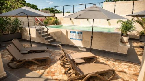 two chairs and an umbrella next to a swimming pool at Hotel Casa Vivaldi in Mérida