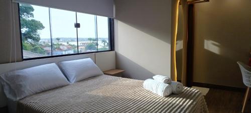 a bedroom with a bed and a large window at Riviera Sanary Praia, Conforto e Tranquilidade in Serra