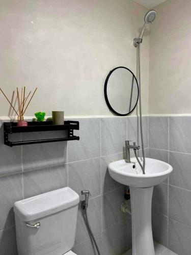 a bathroom with a toilet and a sink and a mirror at Saekyung Condominium in Suba