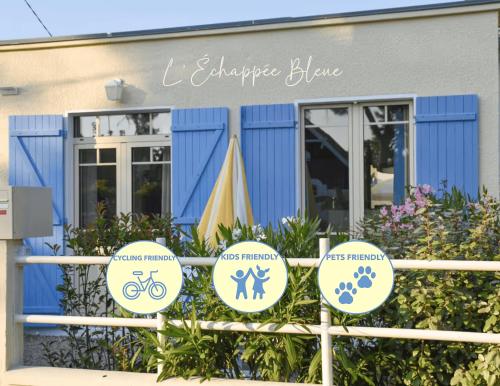 a blue building with signs on a fence at L'Échappée Bleue, maison à 200m de la mer pour vacances et travail in Saint-Brevin-les-Pins