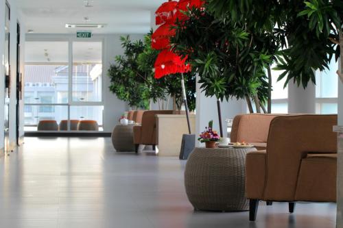 a lobby with chairs and red flowers and plants at b Hotel Bali & Spa in Denpasar