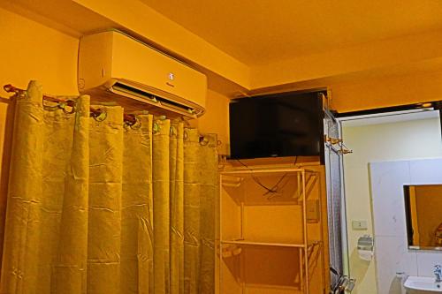 a room with a shower curtain and a television at Point Vista Transient Accomodation in Daet