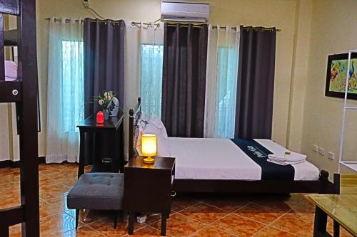 a bedroom with a bed with a lamp and a chair at Point Vista Transient Accomodation in Daet
