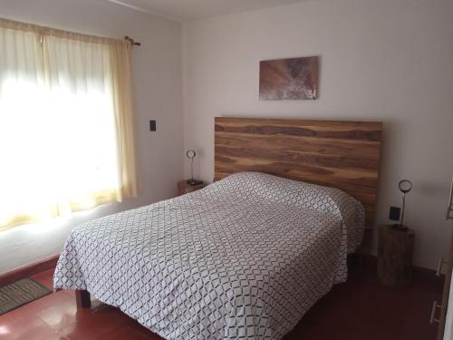 a bedroom with a bed with a wooden headboard and a window at Hotel Casa Capadose in Tlayacapan