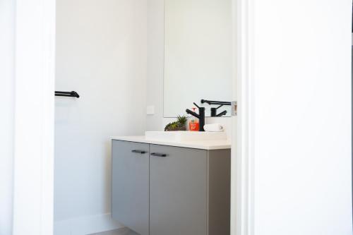 a kitchen with white cabinets and a sink at Huntlee Haven Luxe in North Rothbury