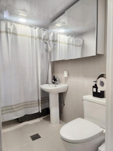 a white bathroom with a toilet and a sink at Mignon Stay FreeParking Near KSPODome AsanMedicalCenter LotteWorldTower in Samgong