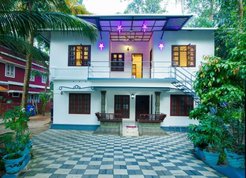 Casa blanca con balcón y patio en Marari White Home, en Alleppey