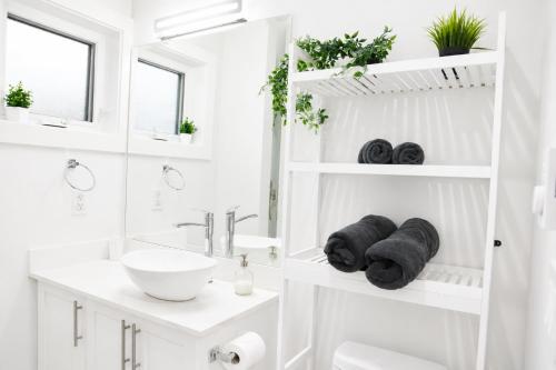 a white bathroom with a sink and a mirror at Centrally Located Modern Suite in North Vancouver