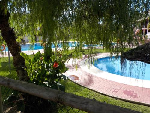 una piscina con un árbol y una valla en Navigolf, en La Cala de Mijas
