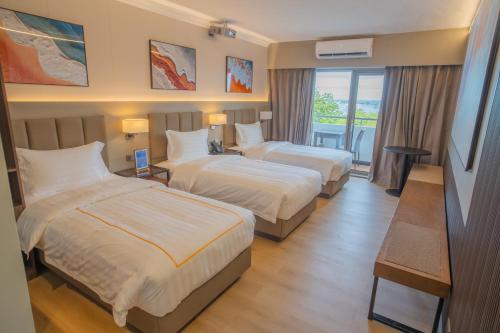 a hotel room with two beds and a balcony at EGI Cebu Resort and Hotel in Maribago