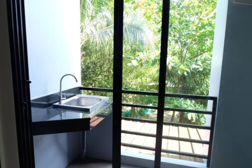 a bathroom with a sink in front of a window at Tha-ruea Residence in Thalang