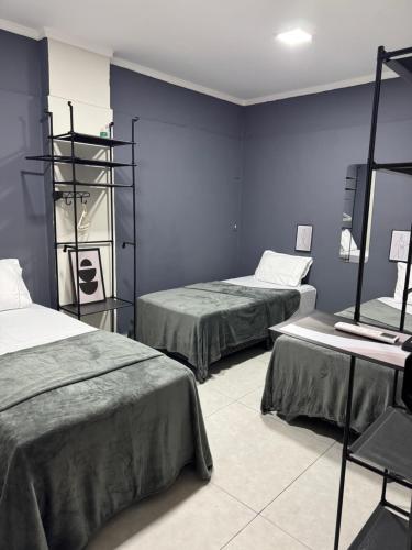 two beds in a room with blue walls at Maia Hostel in Várzea Grande
