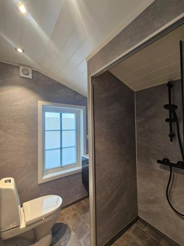ein Badezimmer mit Toilette und Fenster in der Unterkunft Gamlastova in Samlanes