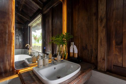a bathroom with a sink and a tub and a mirror at The Palm Tree Bungalow in Xuân Sơn