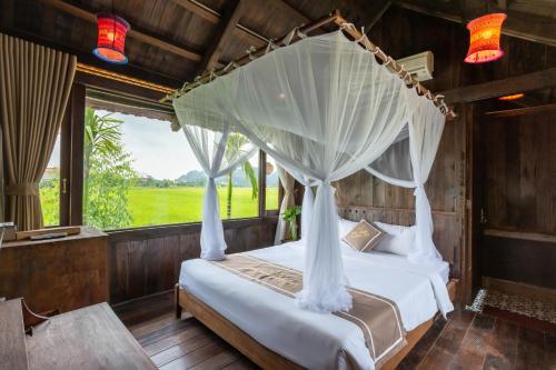 a bedroom with a bed with a canopy at The Palm Tree Bungalow in Xuân Sơn