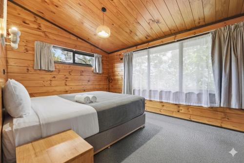 a bedroom with a bed in a wooden cabin at Orewa Motor Lodge in Orewa