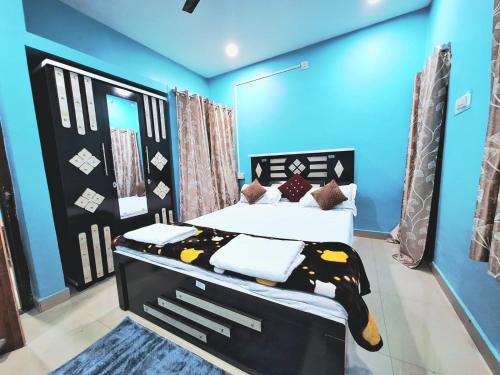 a bedroom with a king sized bed with blue walls at Mona Homestay in Sambalpur
