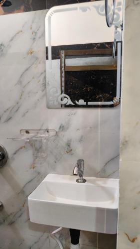 a white bathroom with a sink and a mirror at Hotel SR & restaurant in Bhauvāpār
