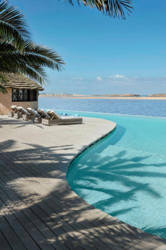 a swimming pool with lounge chairs and the ocean at La Sultana Oualidia in Oualidia