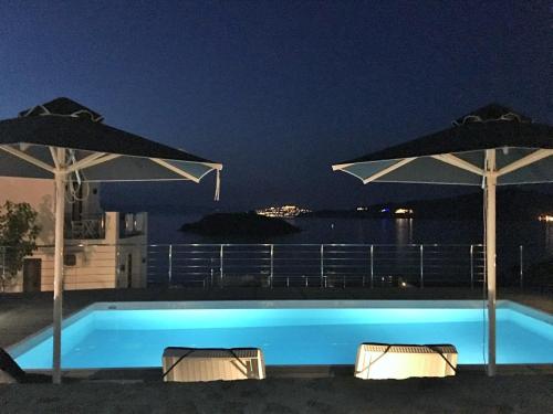 a swimming pool at night with two umbrellas at Eleia Seafront Rooms & Villas in Petra